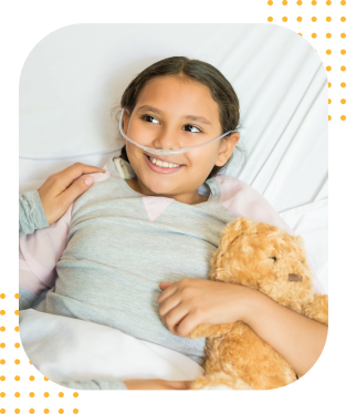 A sick girl cuddled up in bed with her teddy bear.