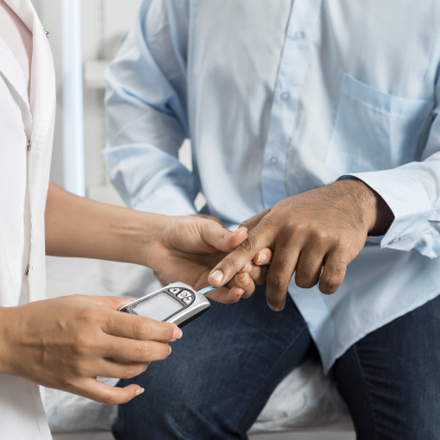 A close-up shot of a medical assistant checks diabetes for a male patient.