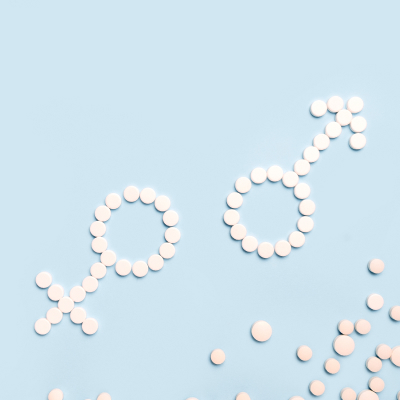 Medical pills in female and male symbol shape on a light blue background.